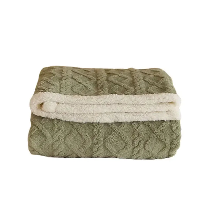 Opgevouwen saliegroene winterdeken met crème lamswollook zijde