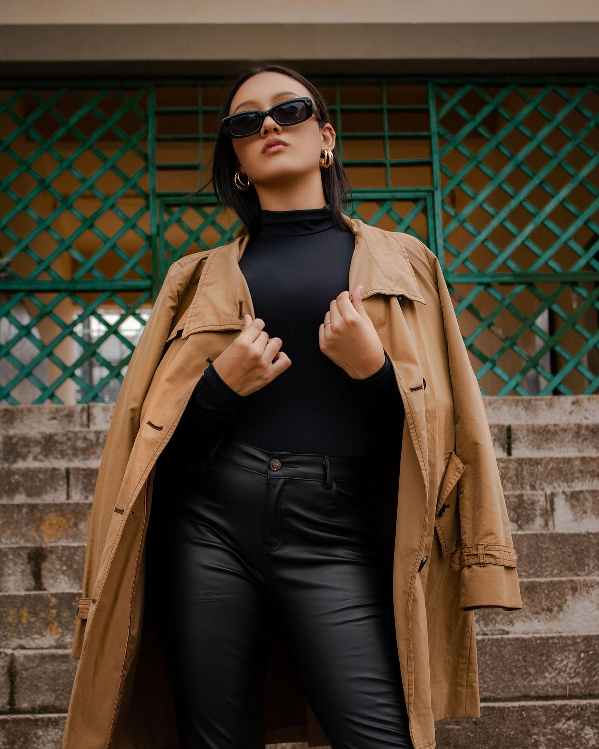 Vrouw in camelkleurige trenchcoat op een stadstrap